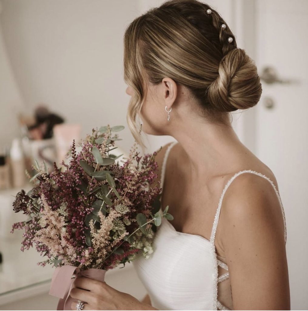 Novia elegante con perlas y moño de boda